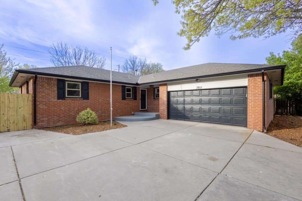 The front of a brick house with a black garage door that we bought fast for cash in Wichita, Kansas